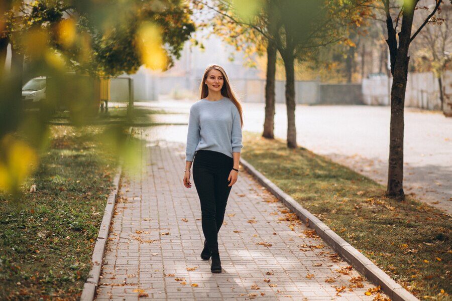 Krásna mladé dievča kráča po mestskom chodníku na jeseň